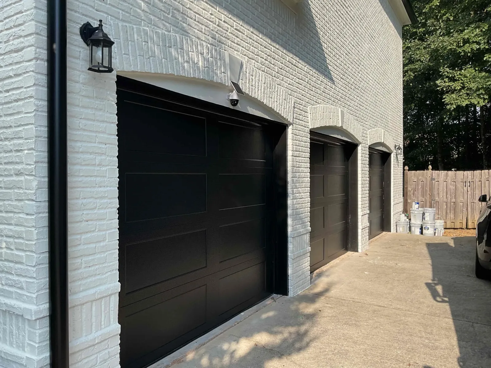 Black garage doors installed on a white brick home