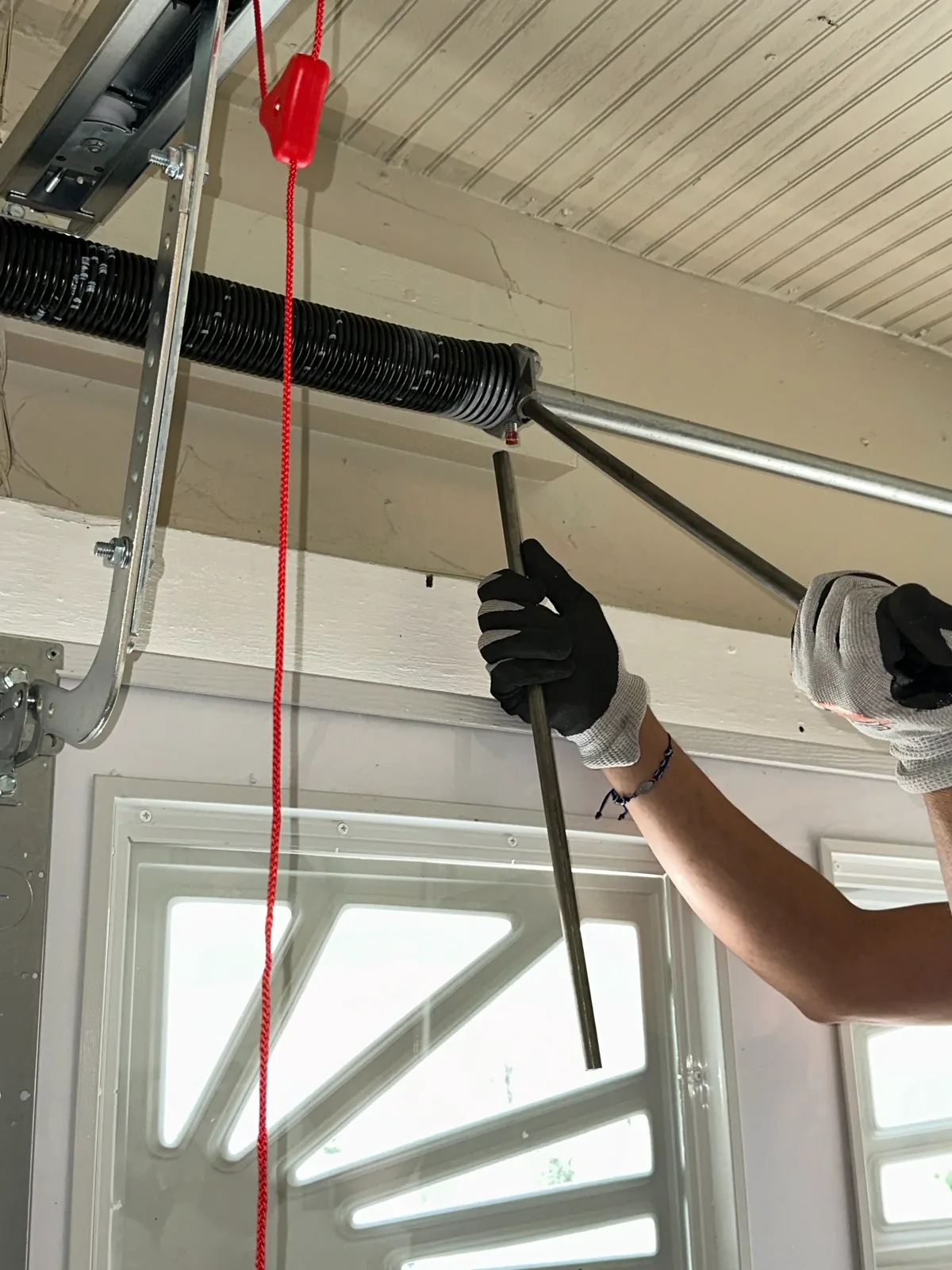 Serenity Garage Doors technician adjusting a torsion spring above a residential garage door